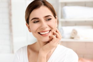 Smiling woman with healthy teeth and radiant smile, showcasing the benefits of ceramic dental implants and holistic dental care.