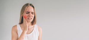 woman holding her jaw due to tooth pain